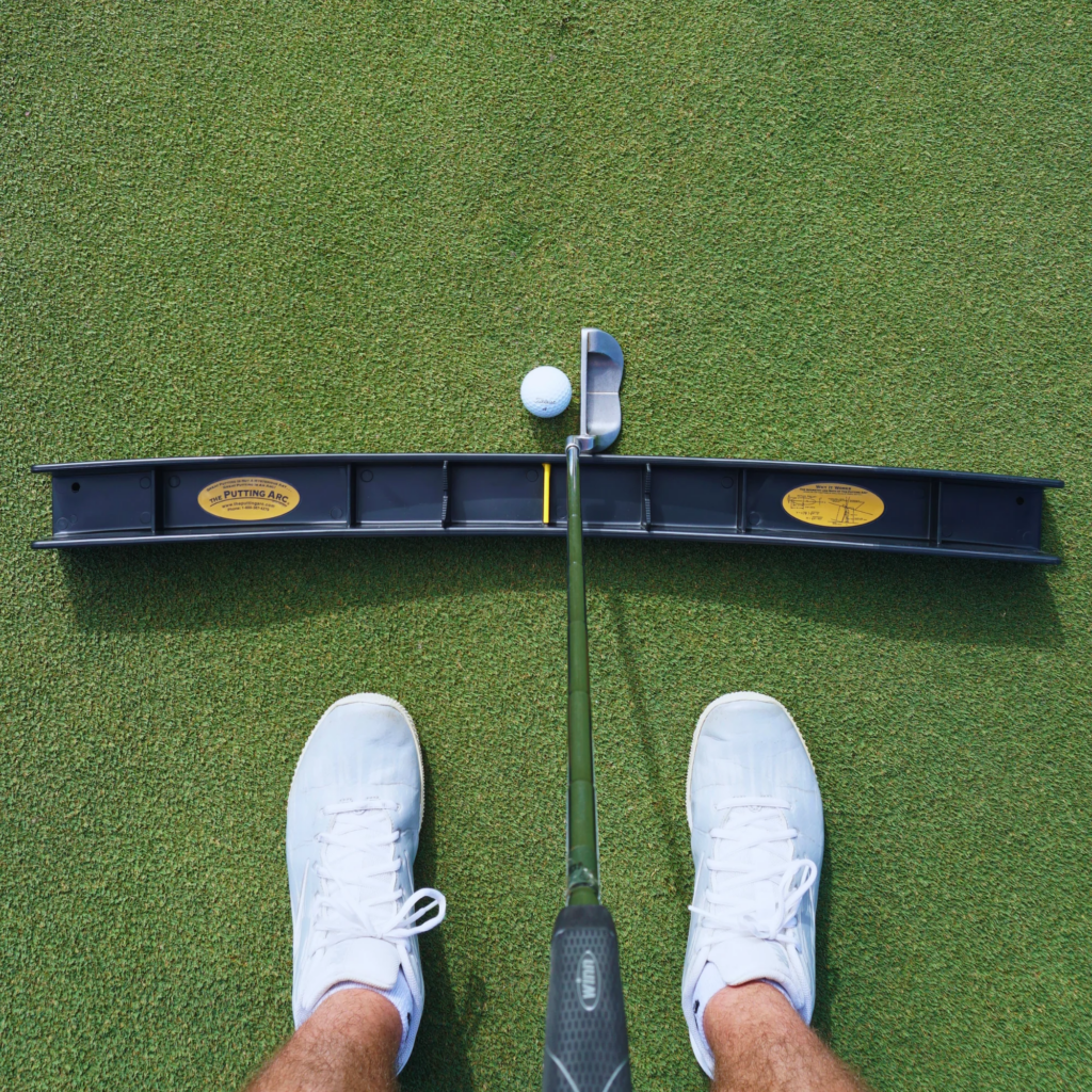 Putting Arc training aid with a putter and golf ball on a practice green
